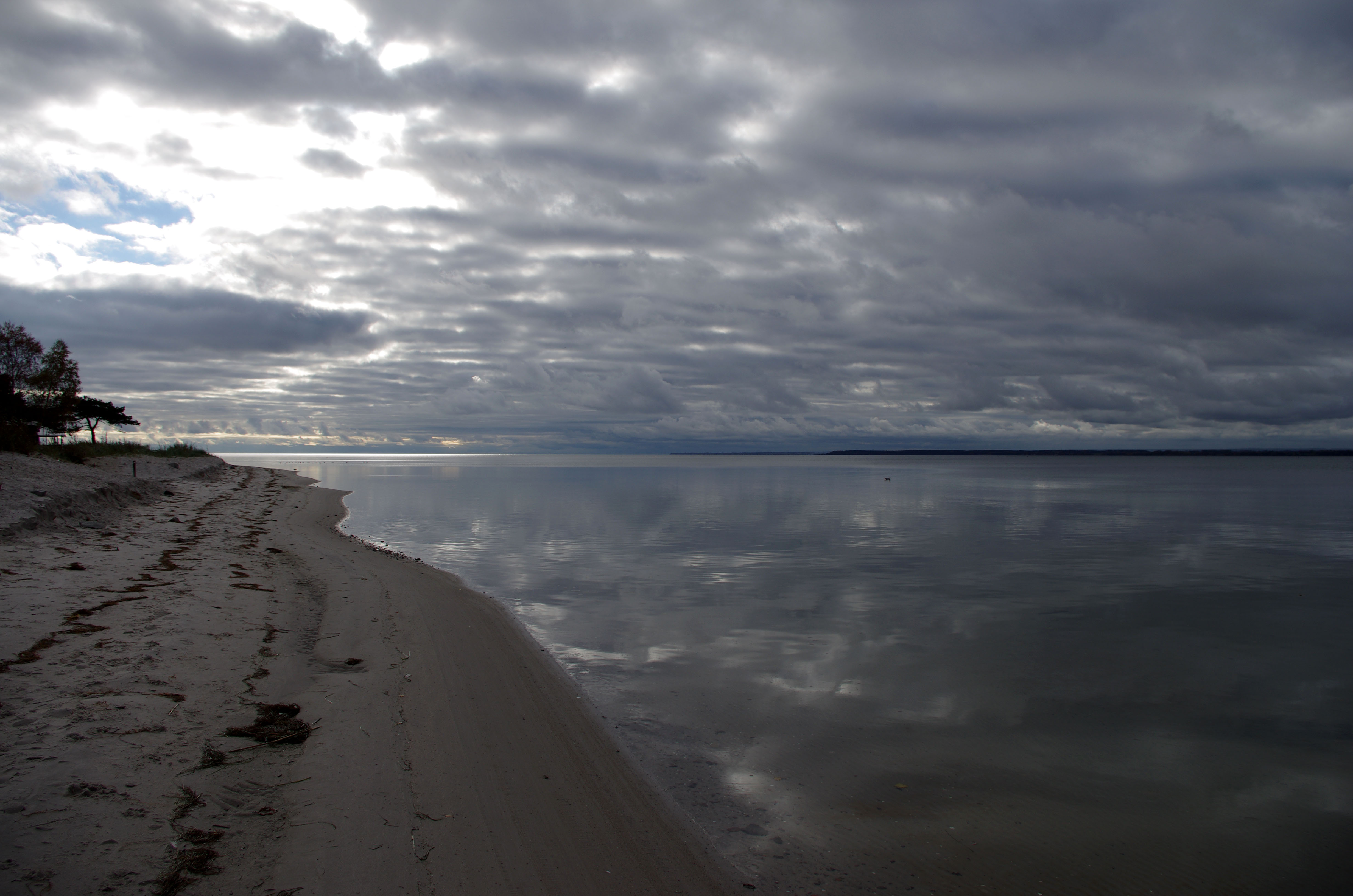 The photo shows a sandy beach bordering on a large shallow bay belonging to the Baltic Sea.